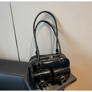 Close-up of black patent leather Boston bag featuring dual front buckle pockets and straps