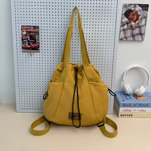 Detail of a bright yellow nylon drawstring backpack with black cords and side pockets