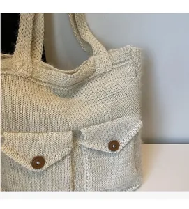 Close-up of knit tote bag featuring large front pockets and brown button detail