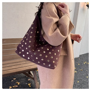Detail of vintage suede tote bag with golden metal studs and wide black shoulder strap