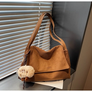 Detail of dark brown suede shoulder bag with magnetic flap and white sheep charm