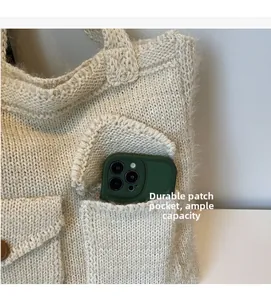 Detail of a beige chunky knit tote bag featuring a durable pocket for smartphone storage
