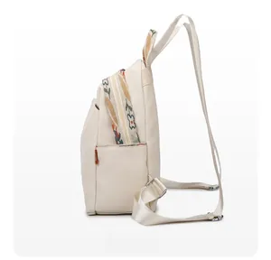 Detail view of the side pocket and floral embroidered straps on the beige backpack