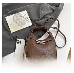 Detail of dark brown lychee grain bucket bag with silver H-shaped clasp and long strap