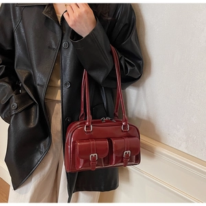 Detail of burgundy glossy faux leather Boston bag with silver buckles and dual straps