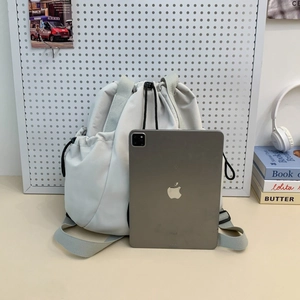 Nylon drawstring backpack in light grey shown next to a tablet for size comparison