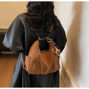 Sac à dos vintage en cuir marron avec zips à franges et ours en peluche sur un mannequin