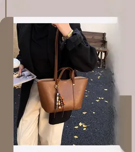 Dettaglio borsa tote in pelle marrone scuro con nappa di perline di legno all'aperto
