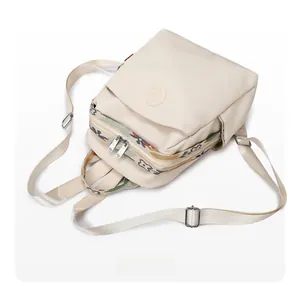 Detail of cream backpack with colorful woven strap and circular embossed logo design