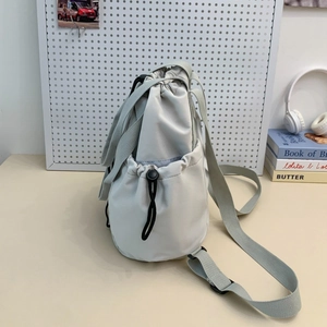 Detail of light grey nylon drawstring backpack with adjustable buckle side pocket