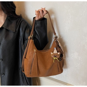Détail d'un sac à bandoulière en similicuir caramel avec breloque d'ours mignonne
