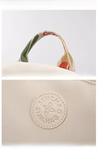 Detail of colorful webbing handle and embossed logo on beige oxford cloth backpack