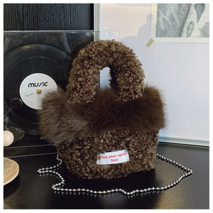 Detail of dark brown faux fur tote bag with silver chain and white spirit free label