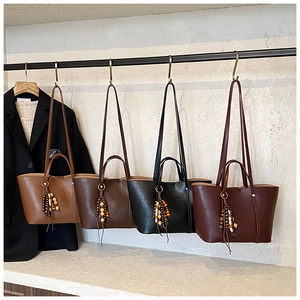 Dettaglio di quattro borse tote vintage in marrone, nero e bordeaux con ciondoli a nappa
