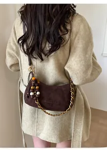 Détail du sac demi-lune en daim marron foncé avec chaîne dorée et bijou de sac ethnique