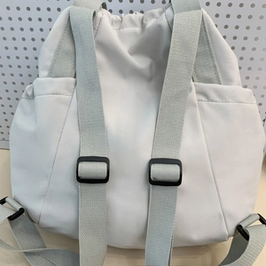 Detail view of reinforced wide woven shoulder straps and black plastic buckles on a nylon bag