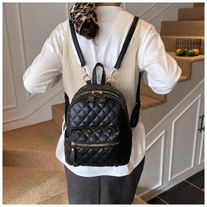 Détail d'un mini sac à dos noir matelassé avec fermetures éclair dorées pour femme