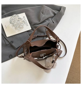 Detail of vintage brown pebble leather bucket bag with silver lock and plush charm