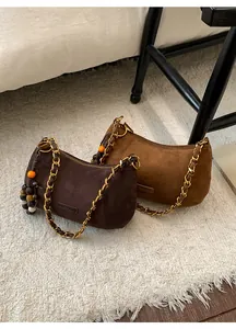 Détail de sacs bandoulière en daim avec chaînes dorées et perles en bois sur tapis