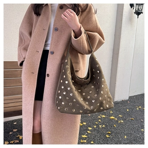 Close-up of olive green suede hobo bag with gold metal rivets and retro aesthetic detail