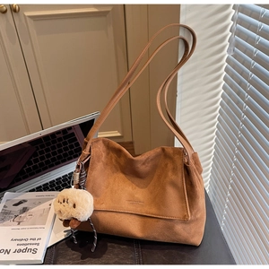 Detailed texture of brown suede tote bag featuring a cute white plush lamb pendant