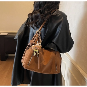 Détail latéral d'un sac à bandoulière en cuir PU caramel avec charms ours et étoile