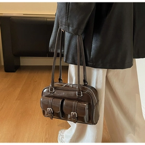 Close-up of vintage brown glossy Boston bag with front pockets and silver hardware