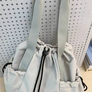 Detail of light gray nylon drawstring bag showing high-density texture and toggle closure