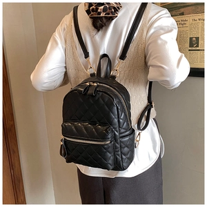 Détail du mini sac à dos noir matelassé avec fermeture dorée porté par un mannequin