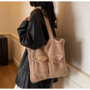 Detail of a large brown crochet shoulder bag with flap pockets and thick knit texture