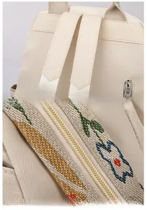 Close-up of wide shoulder straps and floral embroidery detail on beige backpack
