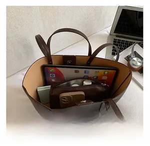 Macro view showing large capacity of brown leather tote bag with iPad and accessories
