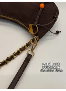Détail du sac en daim marron foncé avec crochets dorés et bandoulière chaîne en cuir