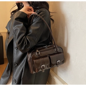 Detail view of a vintage dark brown shoulder bag featuring dual front buckle pockets