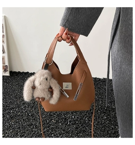 Close-up of brown litchi pattern bucket bag with metal logo and cute rabbit charm detail