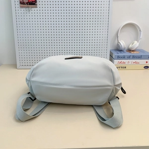 Detail view of the light grey backpack featuring a wide base and durable fabric straps
