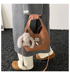 Detail of brown litchi pattern leather bucket bag with a cute plush rabbit charm