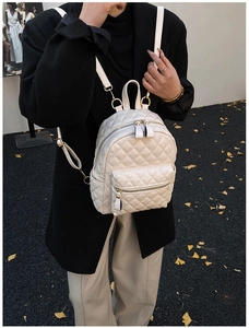 Detail of white quilted leather backpack featuring diamond stitching and gold metal hardware
