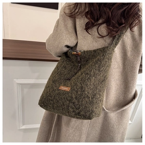 Detail of dark olive green plush bucket bag with leather brand tag and drawstring