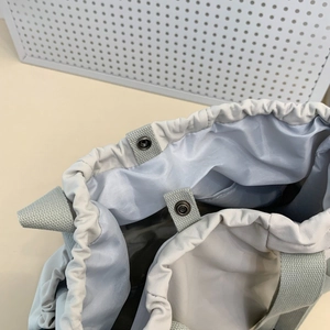 Detail of grey canvas tote featuring drawstring closure and smooth purple lining