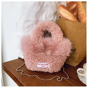 Detail of pink faux shearling mini handbag with silver metal chain and woven text label
