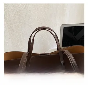 Detail of dark brown leather tote handle with metal rivets and minimalist design