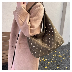 Detail of dark green suede hobo bag with silver rivet studs worn by a model