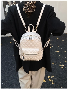 Détail d'un mini sac à dos matelassé chic en similicuir crème porté par un mannequin