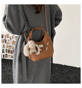 Close-up of vintage brown leather bucket bag with silver lock and plush bunny pendant