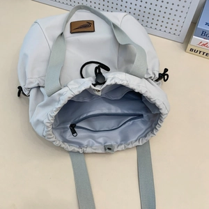 Close-up of drawstring tote bag interior featuring light blue lining and inner zipper pocket