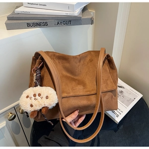Detailed close-up of dark brown suede tote bag with a cute white plush sheep charm