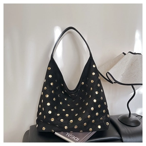 Close-up of black suede hobo bag with gold stud rivets in a minimalist lifestyle setting
