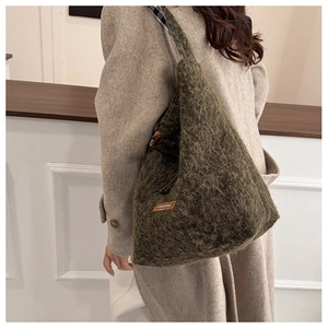 Detail of green fuzzy wool tote bag showing soft texture and brown leather logo patch