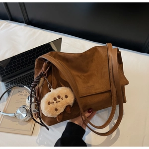 Detail of vintage caramel suede tote bag with plush charm and stylish accessories